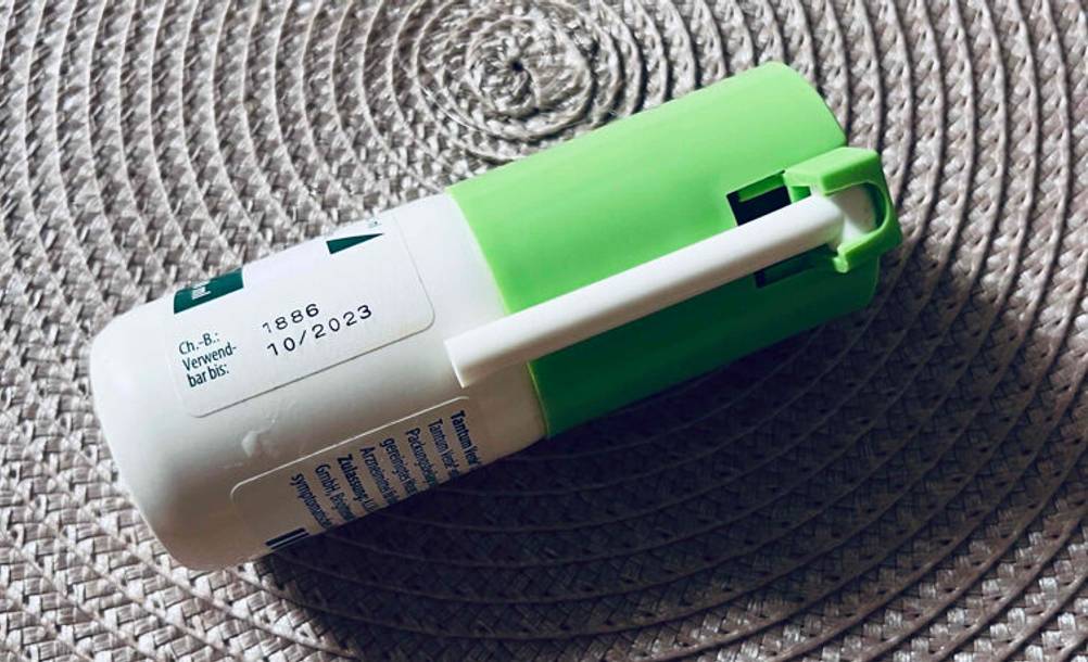 Getestet: Ein Halsspray mit eingeklapptem Zerstäuber liegt auf einer beigefarbenen Oberfläche.