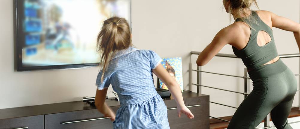 Tanzmatte-Test: Eine Frau und ein Mädchen tanzen vor einem Fernseher.