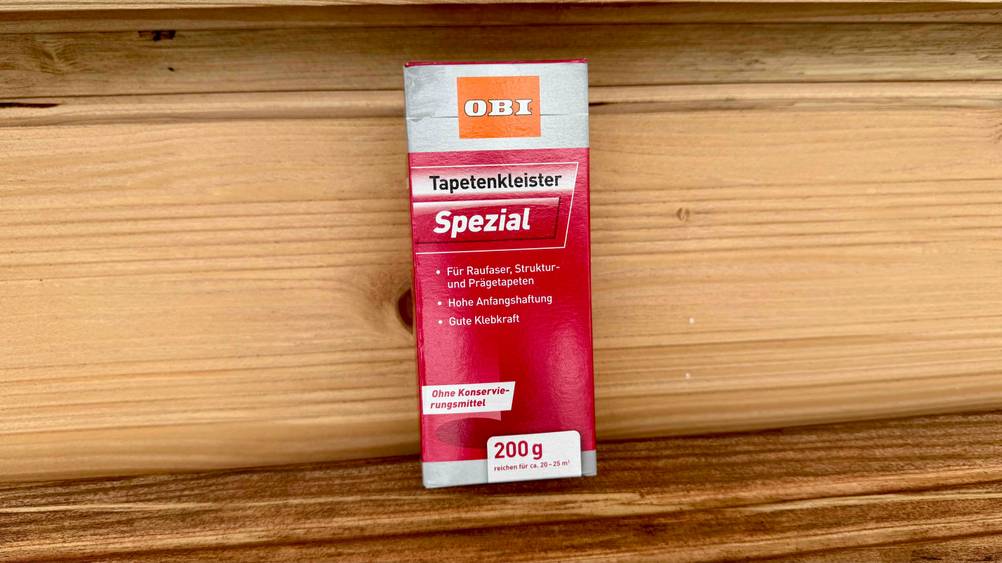 Der getestete Tapetenkleister auf einer Holzfläche stehend.