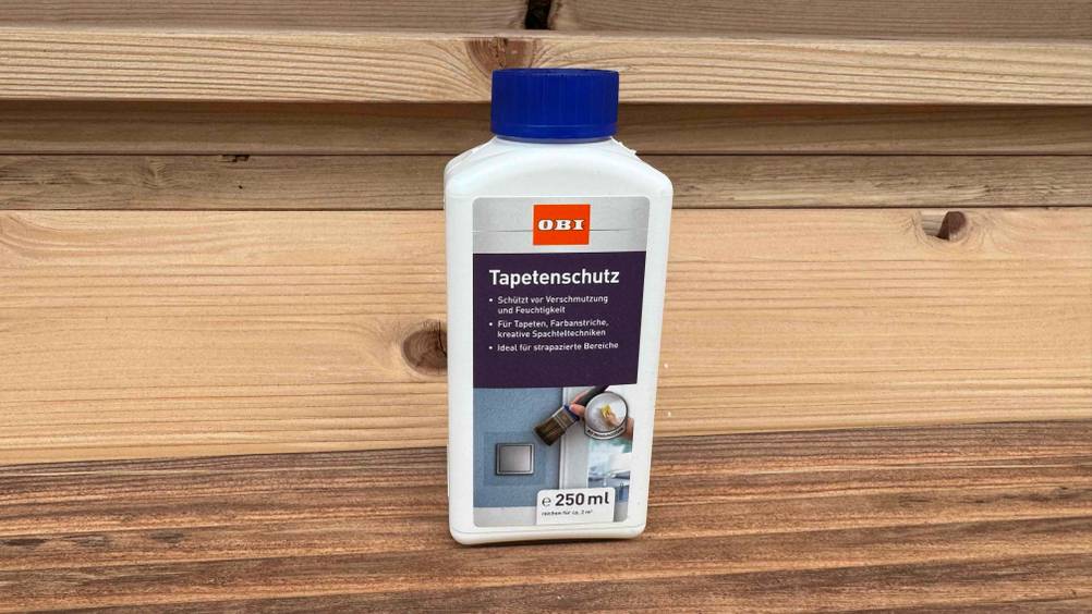 Eine Flasche des getesteten Tapetenschutzes auf einer Holzfläche stehend.