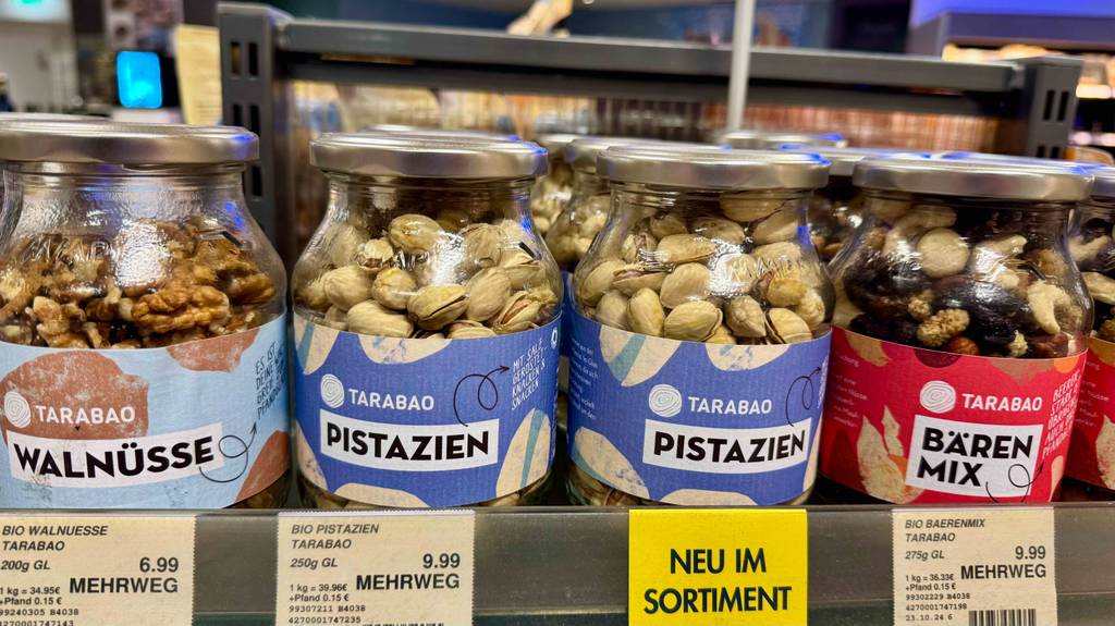 Mehrere Gläser mit Nüssen stehen nebeneinander auf einem Verkaufsregal.