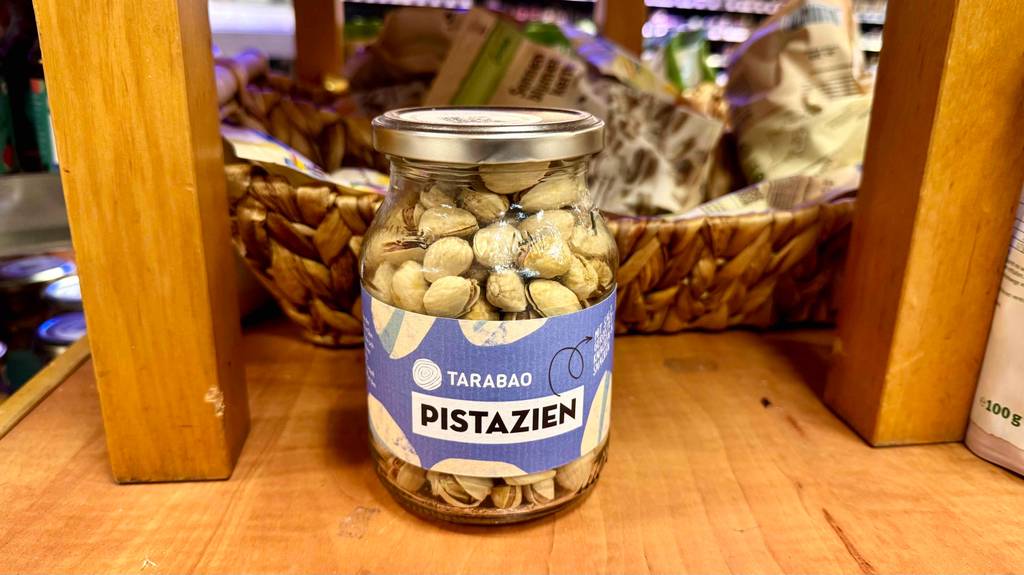 Bio-Pistazien-Test: Pistazien im Glas stehen vor Verpackungen mit Trockenfrüchten.