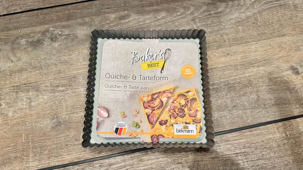Eine getestete Tarteform auf einer Holzfläche von oben.