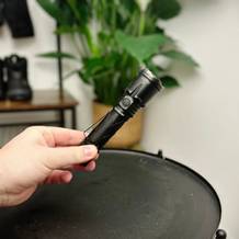 Die Klarus XT21X Pro Taschenlampe wird vollständig ausgepackt und in einer Hand gehalten. Der schwarze Körper mit strukturierter Oberfläche ist gut sichtbar.