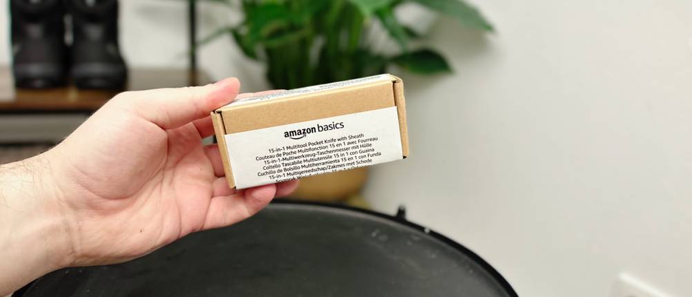 Die Verpackung des Amazon Basics 15-in-1 Multitools liegt in einer Hand. Der Karton ist schlicht mit weißem Etikett gestaltet.