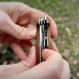 Zwei Hände lösen die Sicherung der ausgeklappten Klinge beim Victorinox Ranger Wood 55. Der Mechanismus wird aus nächster Nähe gezeigt.