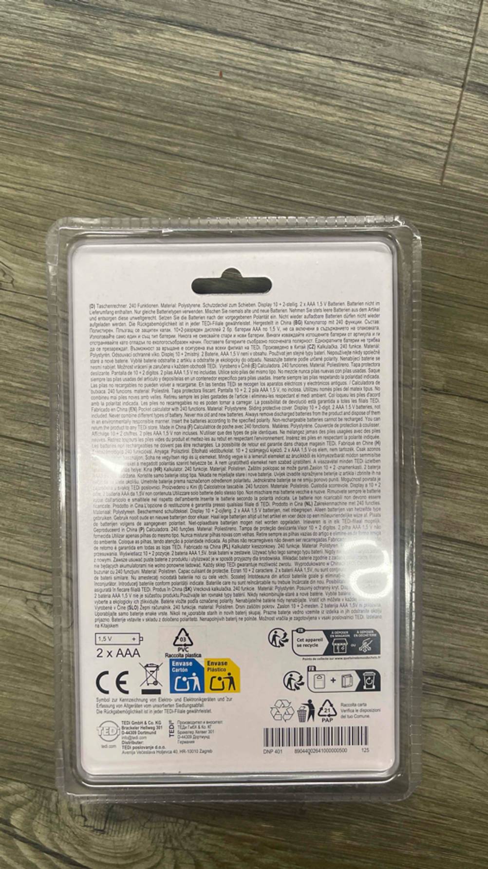 Auf dem Boden liegt der verpackte Taschenrechner (nicht programmierbar) im Test mit der Rückseite nach oben.