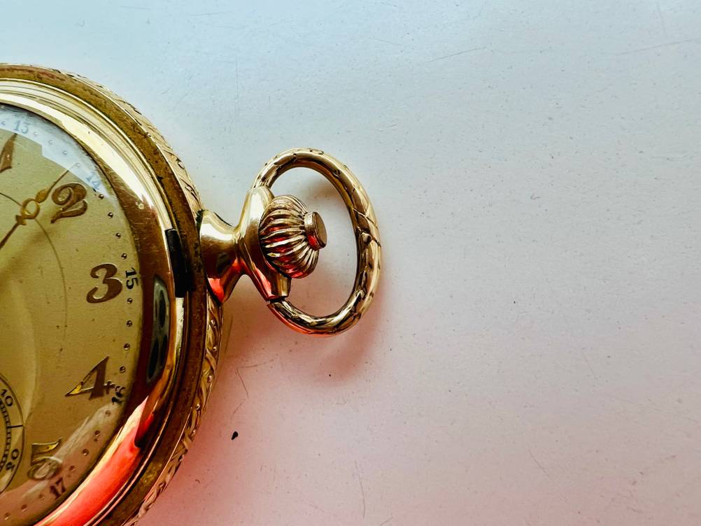Nahaufnahme der Krone einer getesteten Taschenuhr auf einer hellen Fläche.