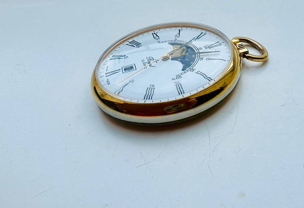 Eine Taschenuhr im Test von schräg seitlich auf einer weißen Fläche liegend.