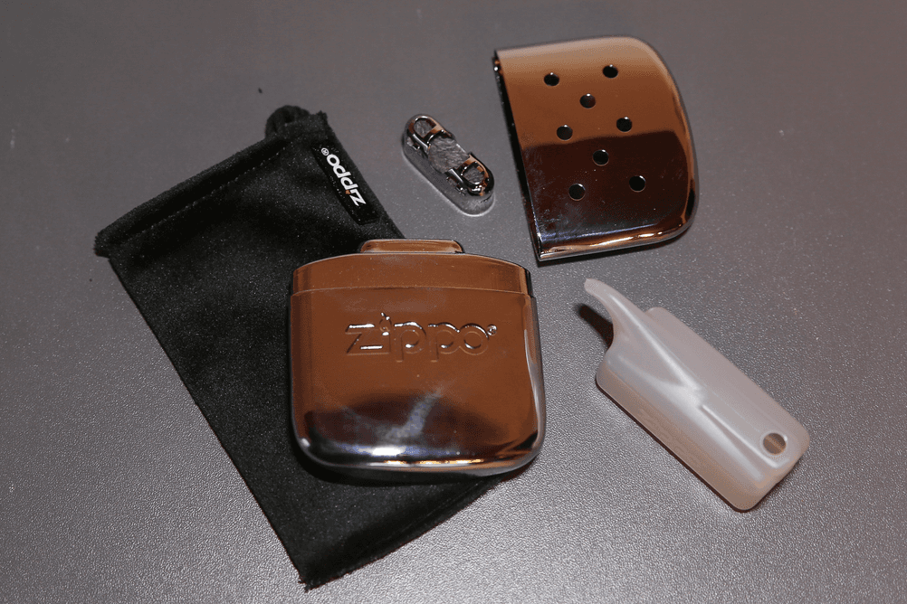 Taschenwärmer im Test: Neben dem Taschenwärmer von Zippo liegt die dazugehörige Abdeckung, der Brenner, eine Schutztasche sowie ein kleiner Kanister.