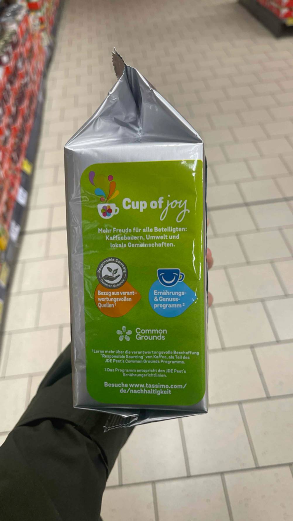 Tassimo-Kapseln im Test. Eine Hand hält eine Packung, so dass die Seite mit Hinweisen zur Umwelt sichtbar ist.