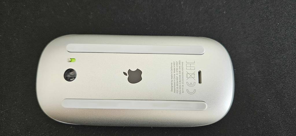 Tastatur-Maus-Set im Test: Eine weiße Apple Maus von unten auf einem schwarzen Untergrund.