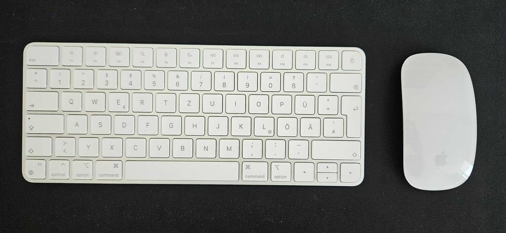 Tastatur-Maus-Set-Test: eine weiße Tastatur mit einer weißen Apple Maus ohne Kabel befindet sich auf einem schwarzen Untergrund.