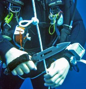 tauchermesser-test: Ein Mann in Taucherausrüstung schneidet unter Wasser ein Seil mit einem Tauchermesser an. 