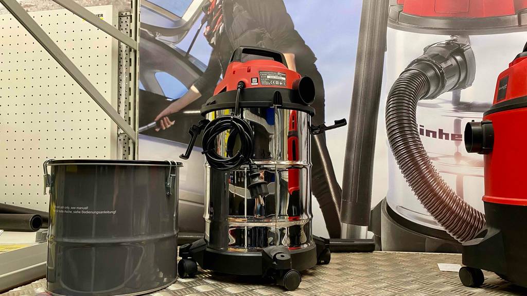 Nass-Trockensauger im Test: ein Einhell-Modell mit Edelstahl-Behälter inklusive schwarz-rotem Deckel befindet sich neben einem roten Sauger in einem Verkaufsbereich.