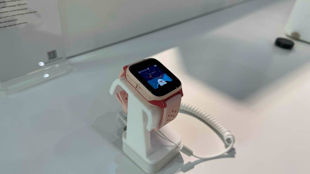 Blick von schräg oben auf eine eingeschaltete Smartwatch für Damen, die zum Testen auf einem weißen Regal steht.