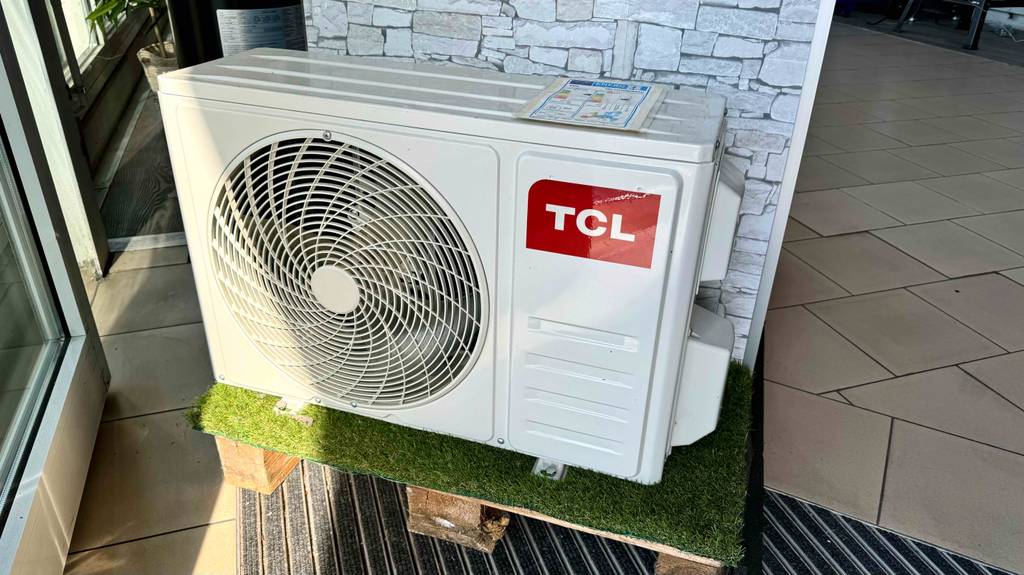 Das Standgerät mit Ventilator einer getesteten Split-Klimaanlage steht auf einem Kunstrasen.