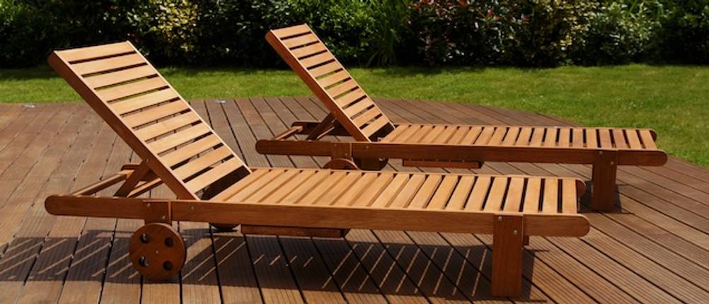 Teak-Gartenliege-Test: Zwei Teak-Gartenliegen stehen auf einem Holzdeck in einem Garten.