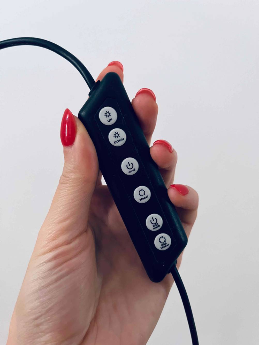 Getestet: Eine Hand hält die Bedienelemente eines Ringlichtes vor eine helle Wand.