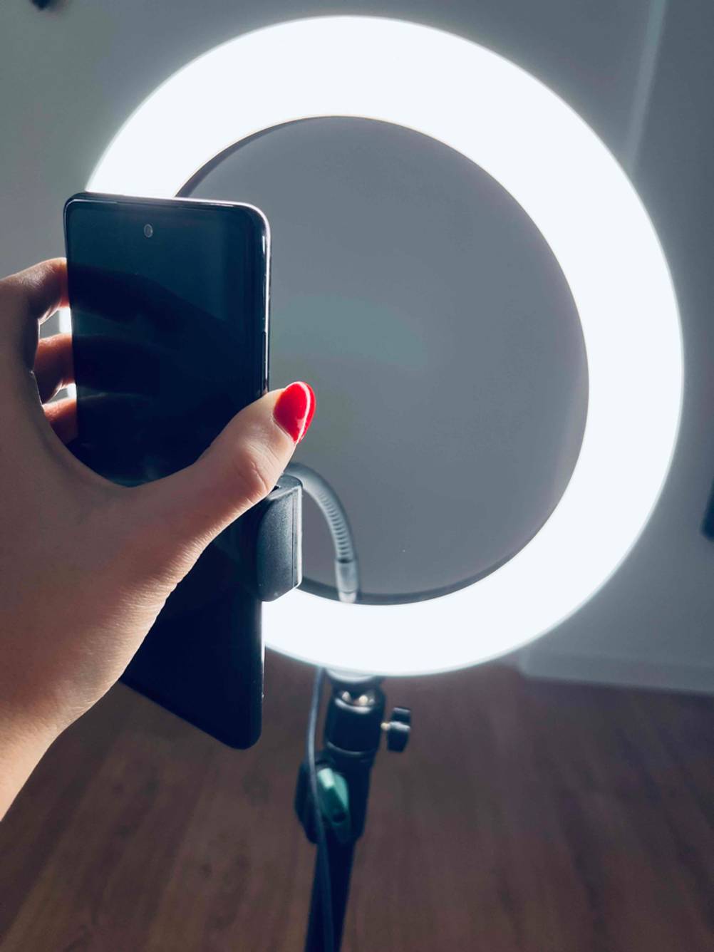 Ein angeschaltenens Ringlicht im Test mit einer Handyhalterung bei der eine Hand ein Handy einsetzt.