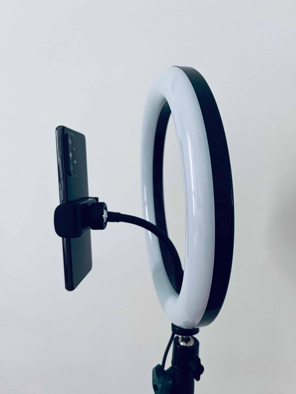 Ein getestetes Ringlicht mit einer beweglichen Handyhalterung von der Seite vor einer hellen Wand.