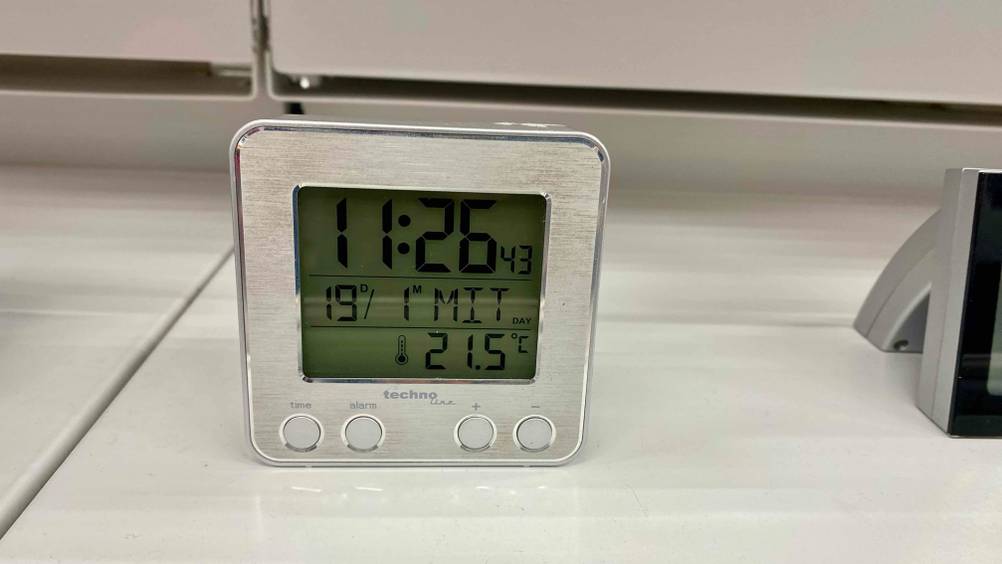 Ein eingeschalteter Funkwecker im Test auf einer hellen Oberfläche von vorne mit Bedienelementen.
