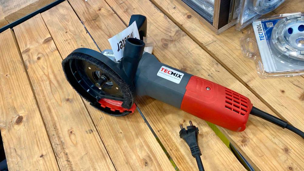 Im Test: Ein Betonschleifer liegt auf einer Holzfläche im Hintergrund andere Produkte.