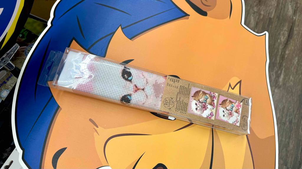 Im Test: Ein verpacktes Diamond-Painting mit Katzendesign liegt auf einem großen Pappkopf.