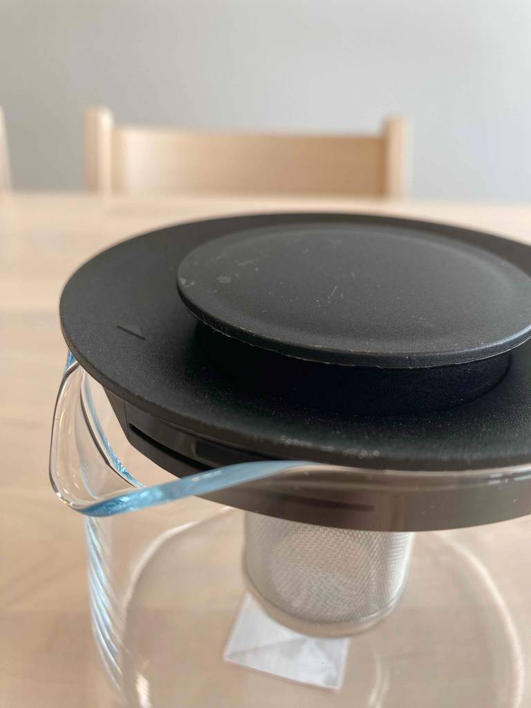 Eine getestete Teekanne aus Glas steht auf einem Holztisch. 