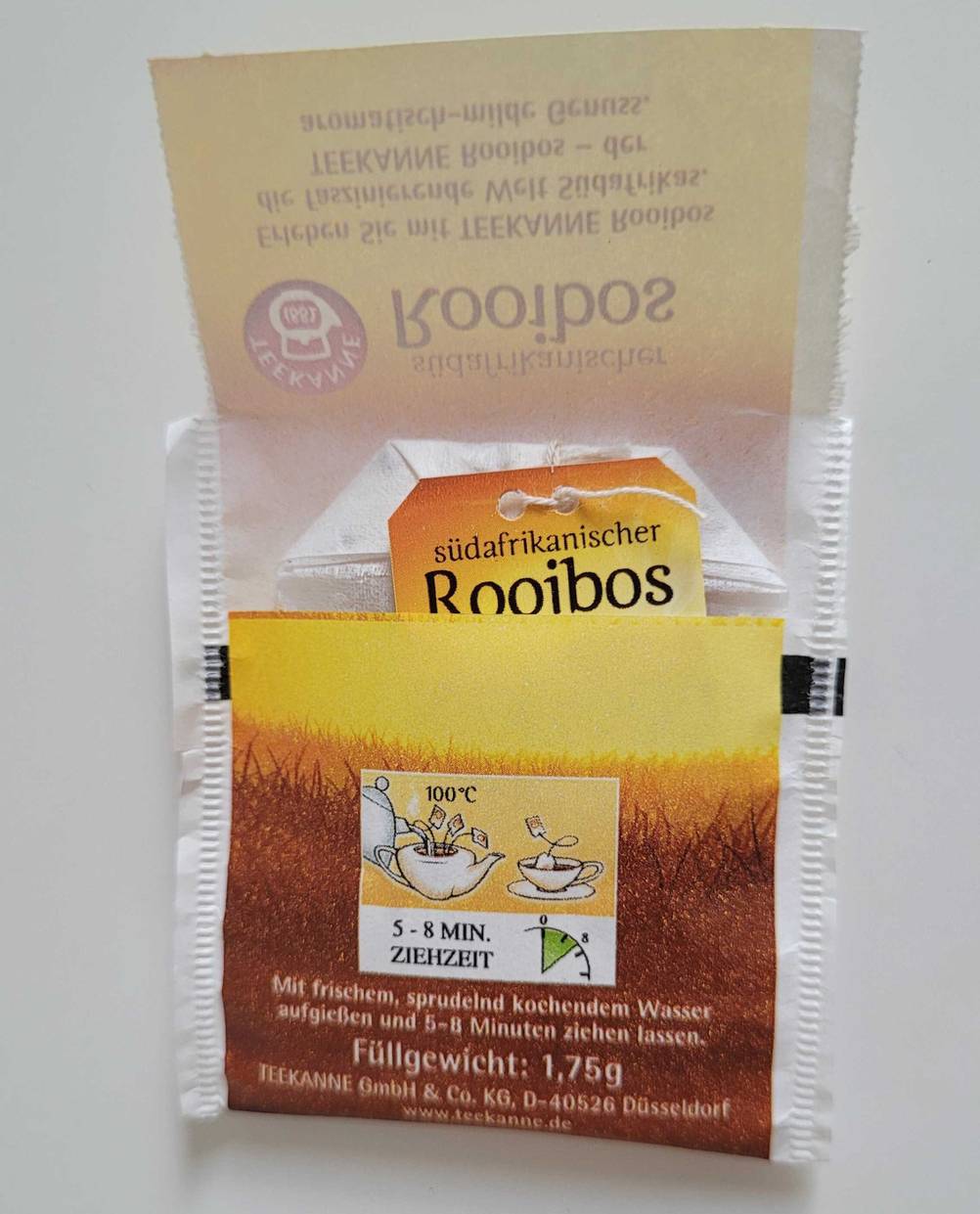 Ein offener Teebeutel mit Rooibos-Tee im Test liegt auf einer weißen Fläche.