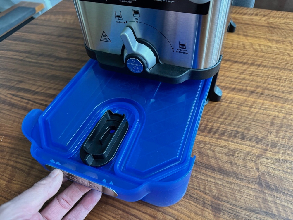 Eine Hand zieht die Ölwanne der Tefal ‎FR8040 heraus