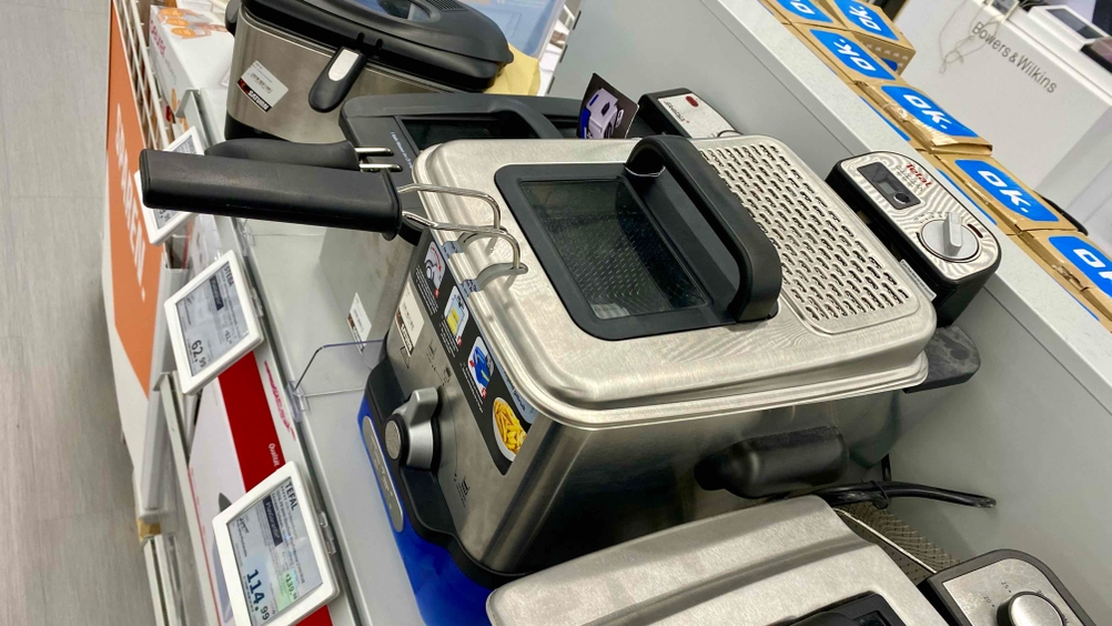 Eine getestete Fritteuse von schräg oben auf einem Verkaufsregal neben anderen Geräten und Preisangaben.