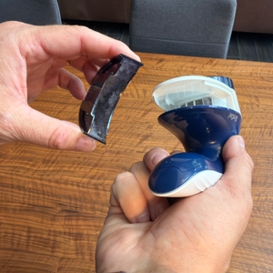 Eine Hand hat den vollen Behälter des Tefal JB1013 nach der Verwendung entfernt