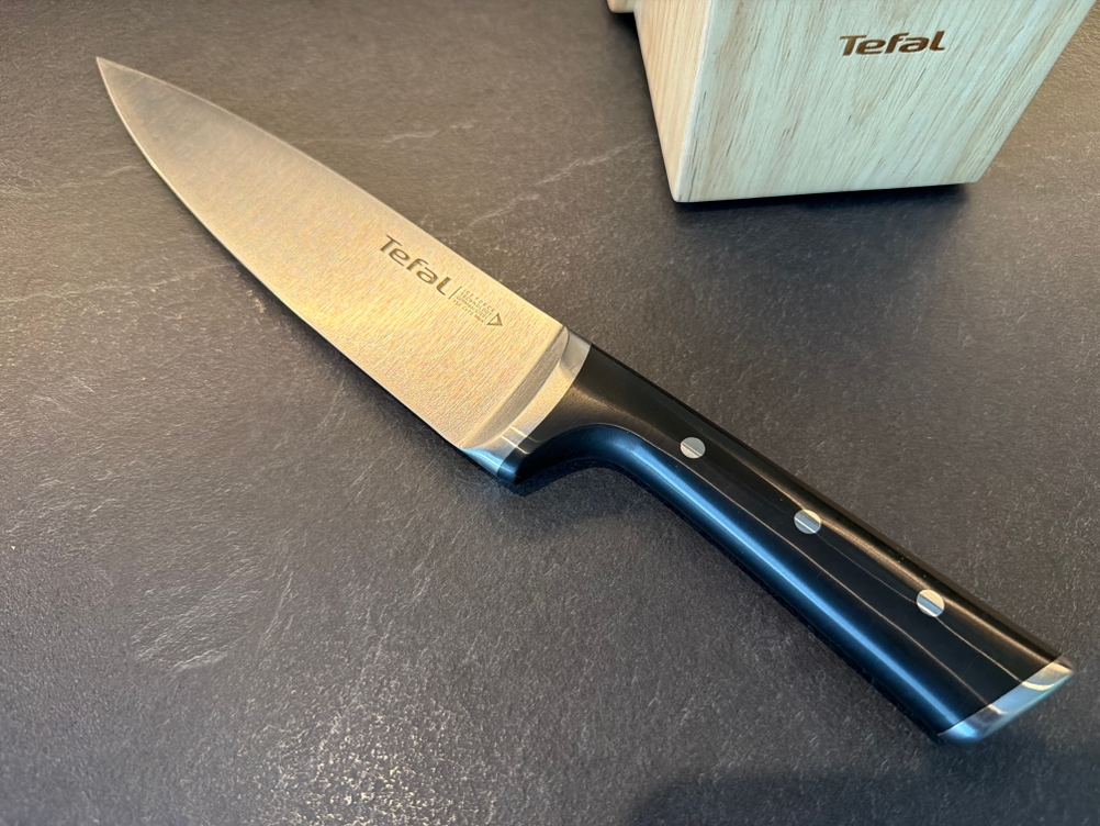 Ein Messer aus dem Tefal K232S574 liegt auf einer Arbeitsplatte.
