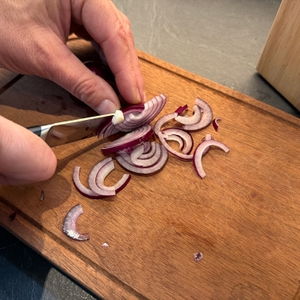 Mit einem Messer aus dem Tefal-K232S574-Messerset wird eine Zwiebel geschnitten.