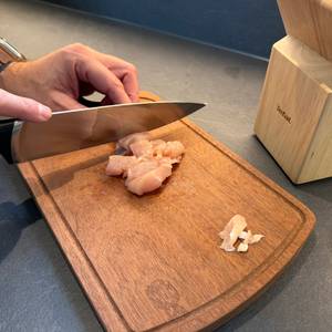 Mit einem Messer vom Tefal-K232S574-Messerset wird Fleisch geschnitten.