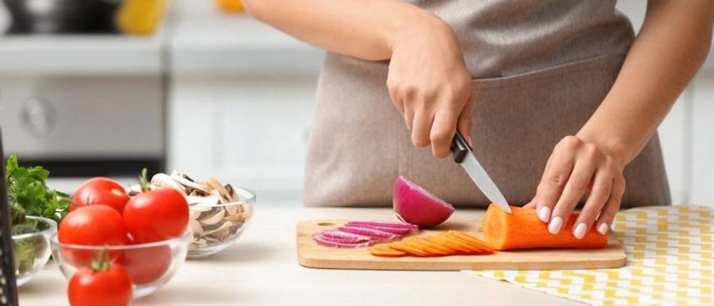 Tefal-Messer-Test: Zwiebel und Karotten werden auf einem Schneidebrett geschnitten.