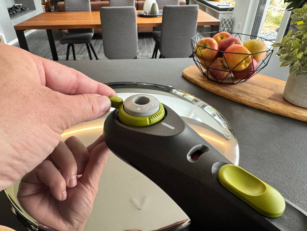 Eine Hand stellt etwas an einem Regler auf dem Deckel des Tefal P2530737 ein.