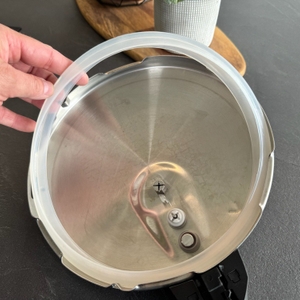 Eine Hand entfernt die Gummidichtung aus dem Deckel des Tefal P2530737.