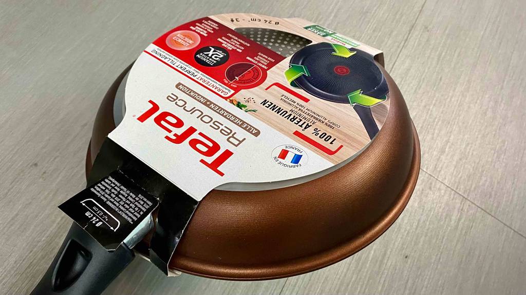 Tefal-Pfanne im Test: eine rostbraune Pfanne von Tefal in ihrer Originalverpackung liegt mit dem Boden nach oben auf einer hellen Oberfläche.