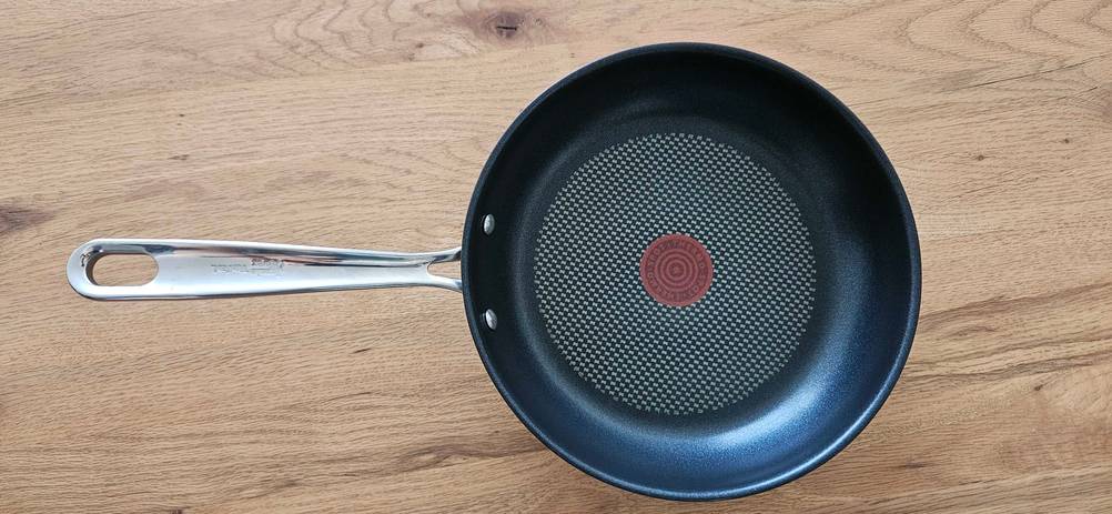 Eine getestete Tefal Pfanne horizontal auf einer Holzoberfläche stehend.