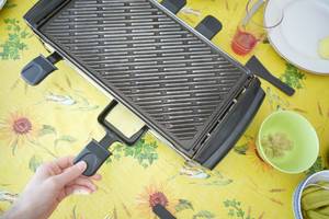 Tefal-Raclette-Test: auf einem Tisch steht ein Raclette mit Grillplatte. 