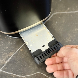 Eine Person zieht die Krümelschublade aus dem getesteten Toaster von Tefal.