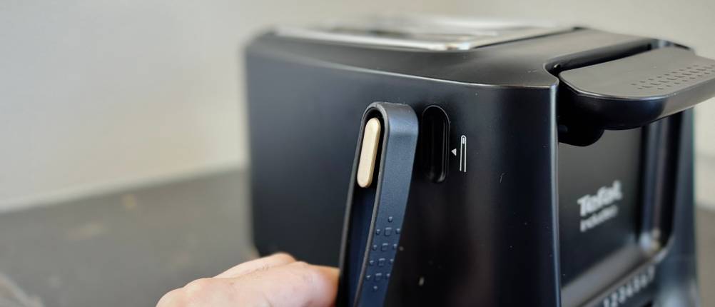 Toaster im Test: Eine Person nimmt die Zange vom getesteten Tefal-Toaster in die Hand.