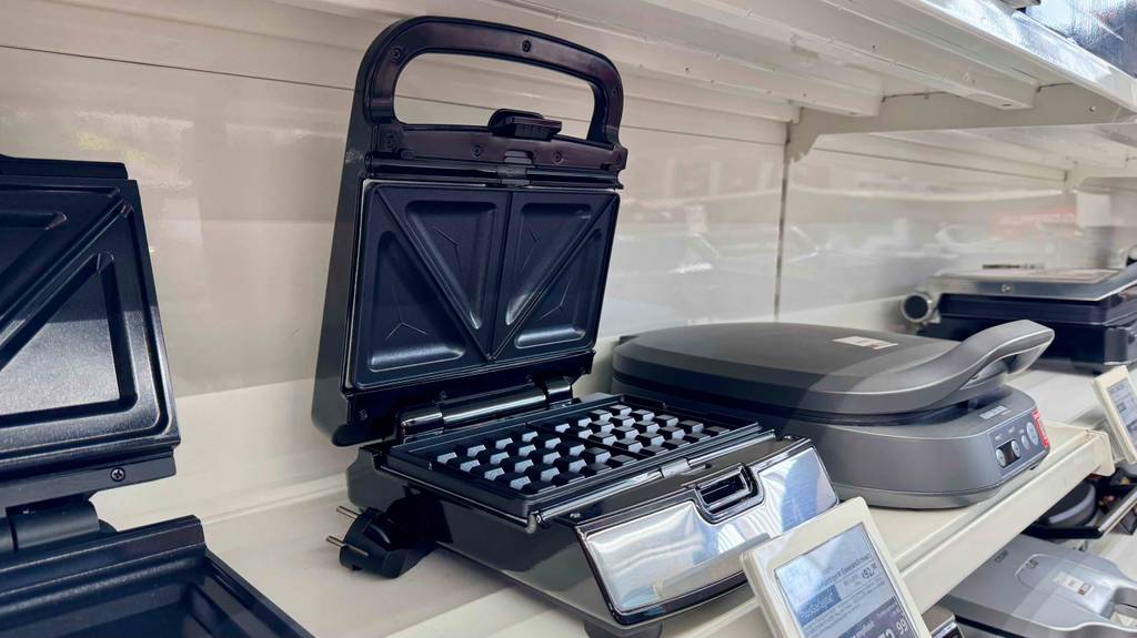 Ein Tefal-Waffeleisen steht zum testen mit offenem Deckel neben anderen Geräten.
