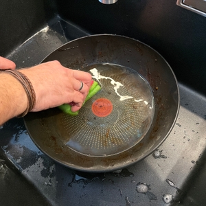 Eine Hand wischt mit einem Schwamm durch die Tefal-Wokpfanne Unlimited On