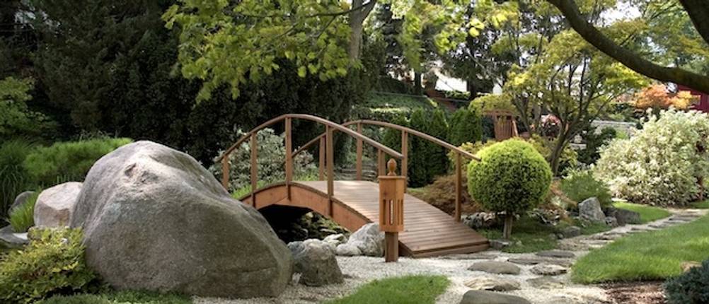 Getestete Teichbrücke aus Holz mit Geländer in einem japanischen Garten.