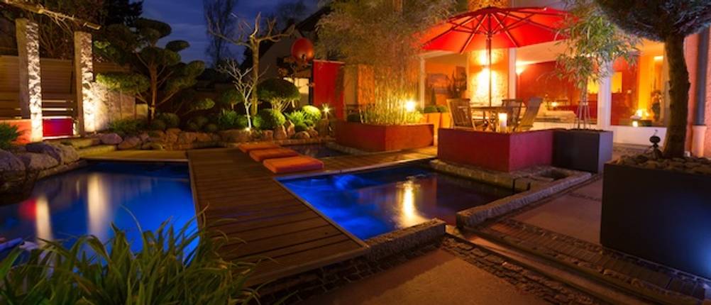 Eine getestete gerade Teichbrücke aus Holz führt über einen Pool bei Nacht.