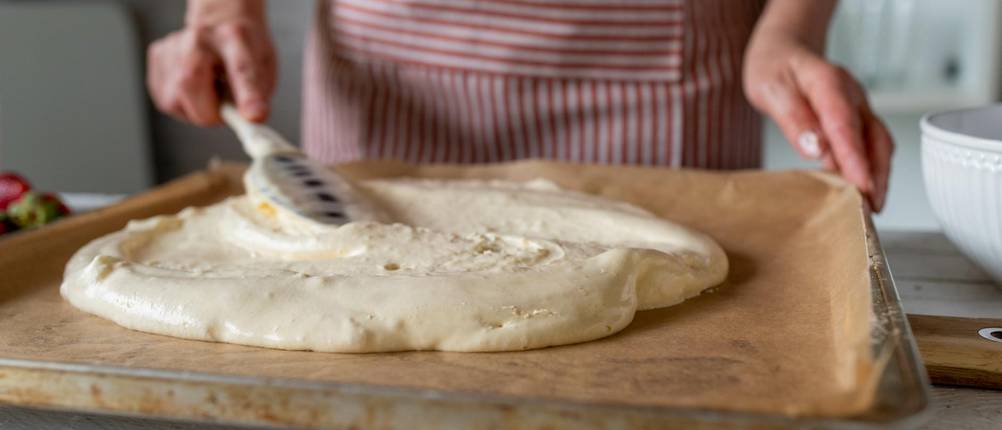 Teigkarten im Test: Teig wird mit einem Teigschaber auf einem Blech verteilt.