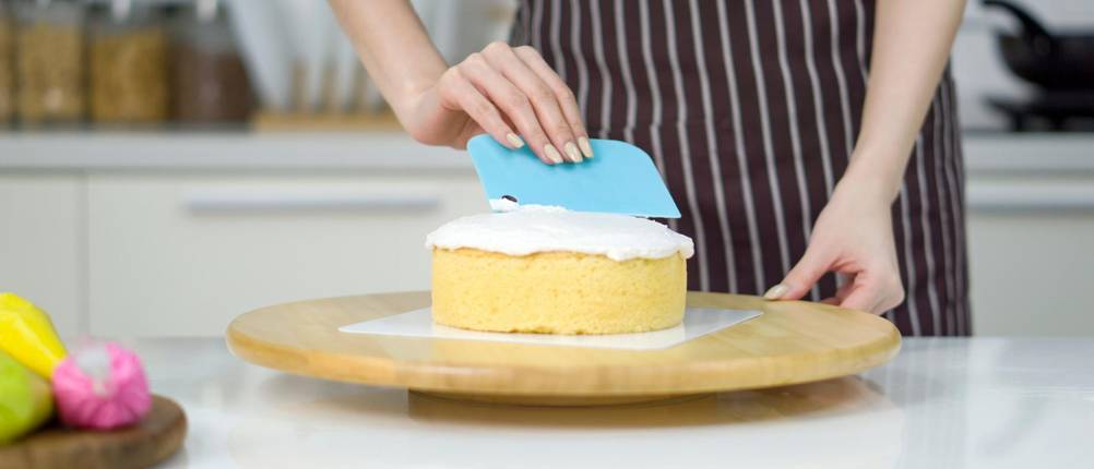 Teigkarten im Test: Eine Frau verstreicht Creme auf einem Mini-Kuchen mit einer Teigkarte.